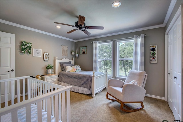 bedroom featuring ceiling fan, a closet, crown molding, and a crib