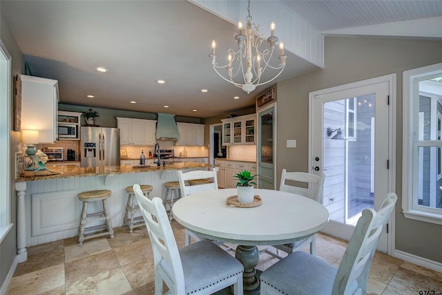 dining area with lofted ceiling, a healthy amount of sunlight, and an inviting chandelier