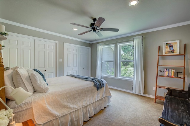 carpeted bedroom featuring ceiling fan, crown molding, and two closets