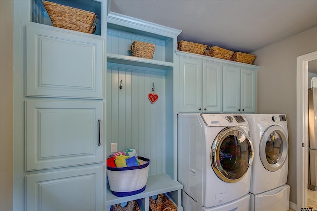 clothes washing area featuring cabinets and washing machine and clothes dryer