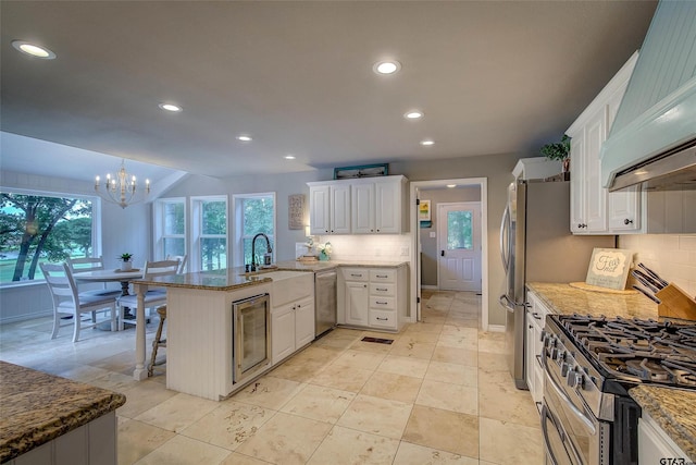 kitchen with white cabinets, appliances with stainless steel finishes, sink, a notable chandelier, and a breakfast bar area