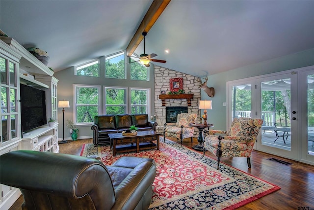 living room featuring ceiling fan, vaulted ceiling with beams, wood-type flooring, and a stone fireplace