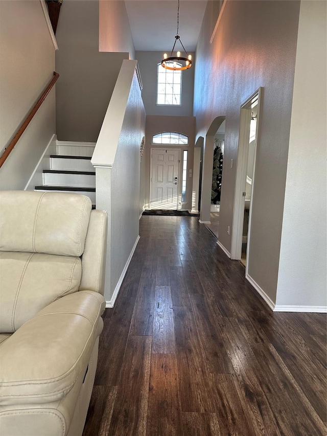 entrance foyer featuring a notable chandelier, a towering ceiling, and dark hardwood / wood-style floors