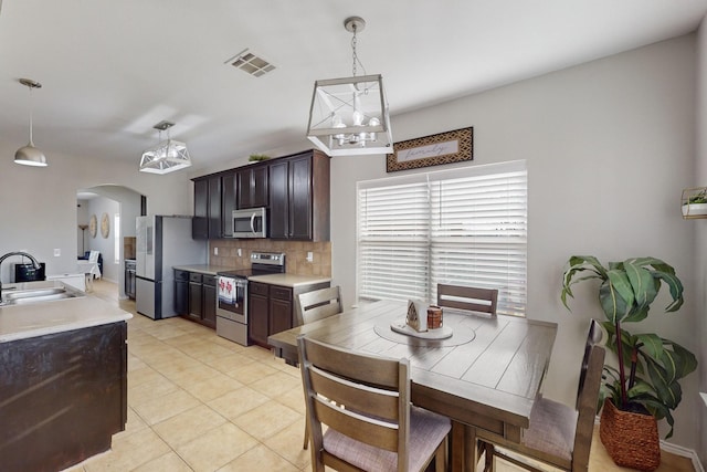 kitchen with tasteful backsplash, sink, decorative light fixtures, and appliances with stainless steel finishes