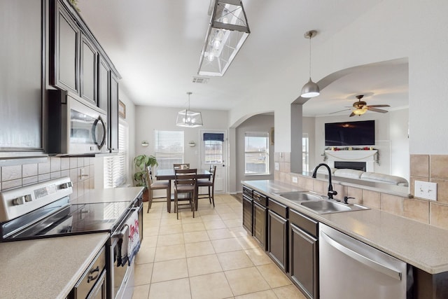 kitchen featuring sink, appliances with stainless steel finishes, pendant lighting, ceiling fan with notable chandelier, and backsplash