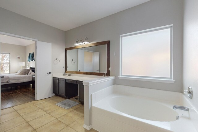 bathroom featuring tile patterned floors, tiled bath, and vanity