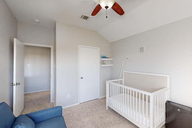 bedroom featuring a crib, lofted ceiling, light colored carpet, and ceiling fan