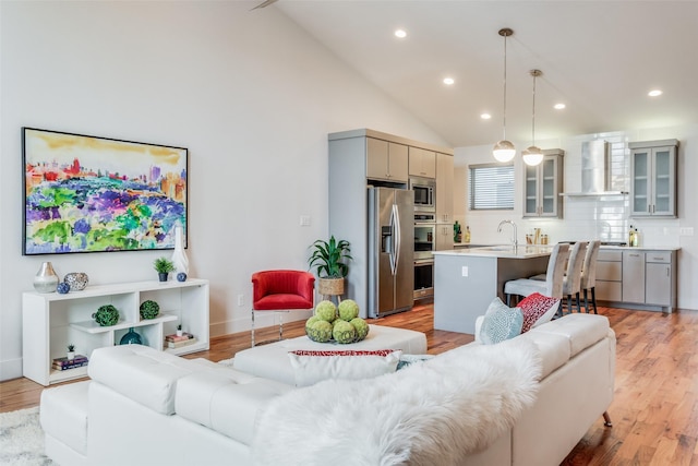 living room featuring sink, light hardwood / wood-style floors, and high vaulted ceiling