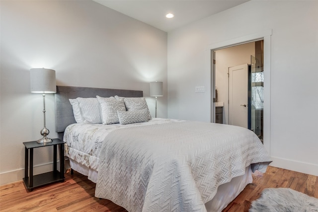 bedroom with ensuite bathroom and hardwood / wood-style flooring