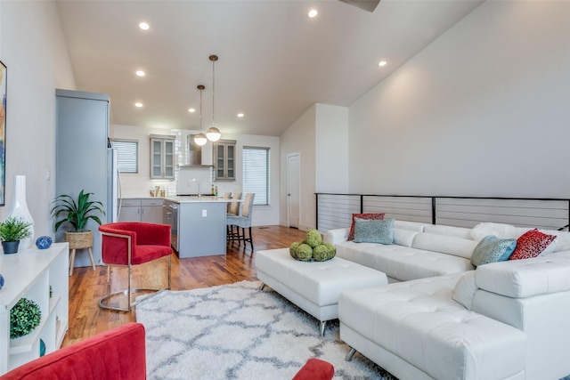 living room with sink, lofted ceiling, and light wood-type flooring