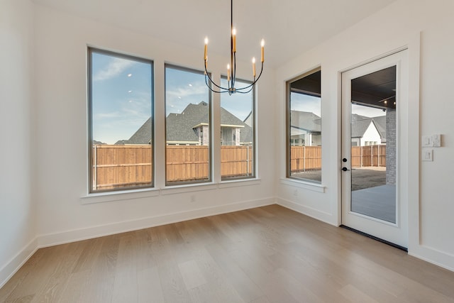 unfurnished dining area featuring light hardwood / wood-style floors, an inviting chandelier, and a healthy amount of sunlight