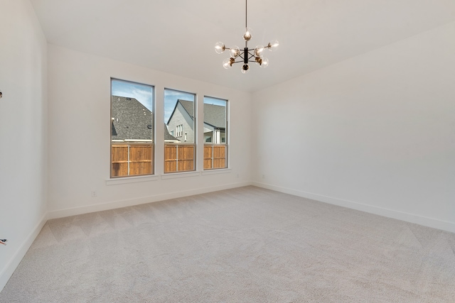 carpeted empty room featuring an inviting chandelier