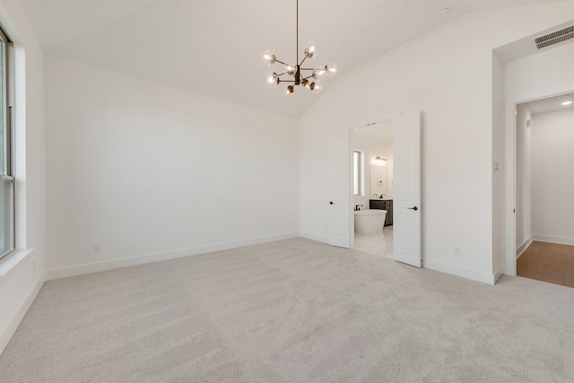 carpeted empty room featuring high vaulted ceiling and a notable chandelier