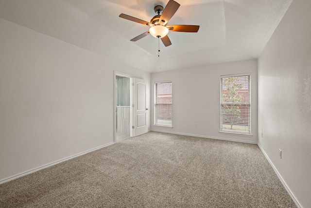 empty room with ceiling fan, carpet, and a raised ceiling