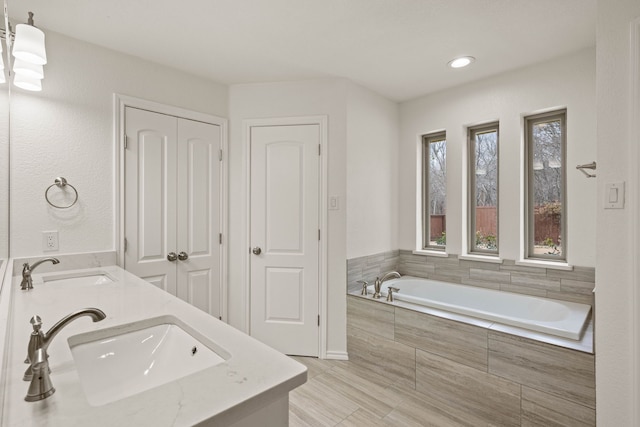 bathroom featuring tiled bath and vanity