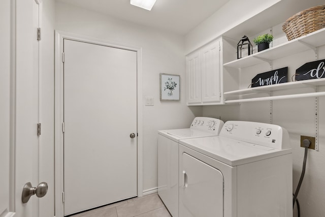 laundry area with washer and dryer, cabinets, and light tile patterned floors