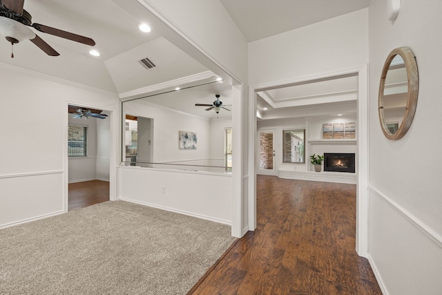 unfurnished living room with dark wood-type flooring, ornamental molding, lofted ceiling, and a large fireplace