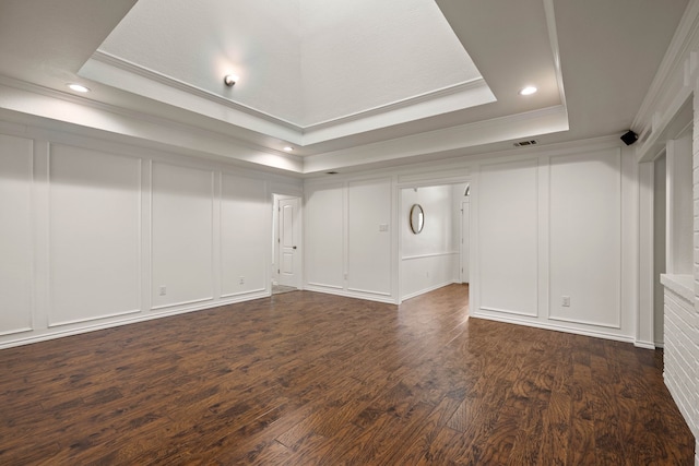 unfurnished room with dark wood-type flooring, a tray ceiling, and ornamental molding