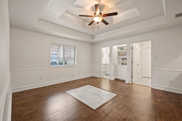 spare room featuring a raised ceiling, ceiling fan, dark hardwood / wood-style floors, and crown molding