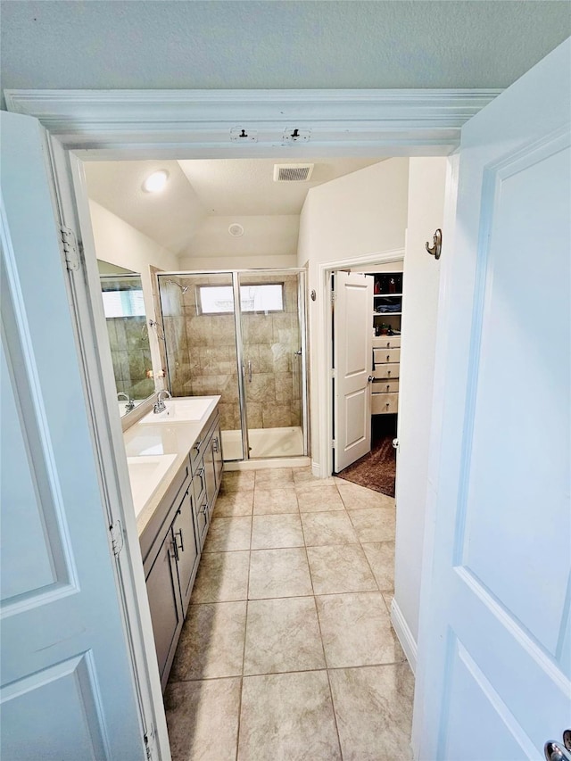 bathroom with walk in shower, vanity, vaulted ceiling, and tile patterned flooring