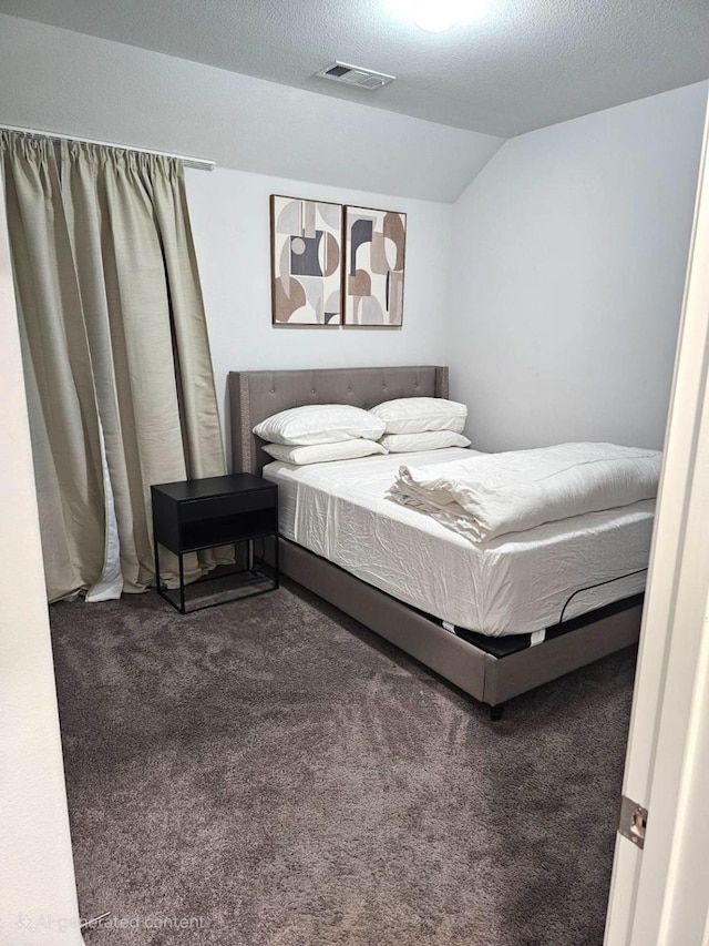 bedroom featuring a textured ceiling, lofted ceiling, and dark carpet