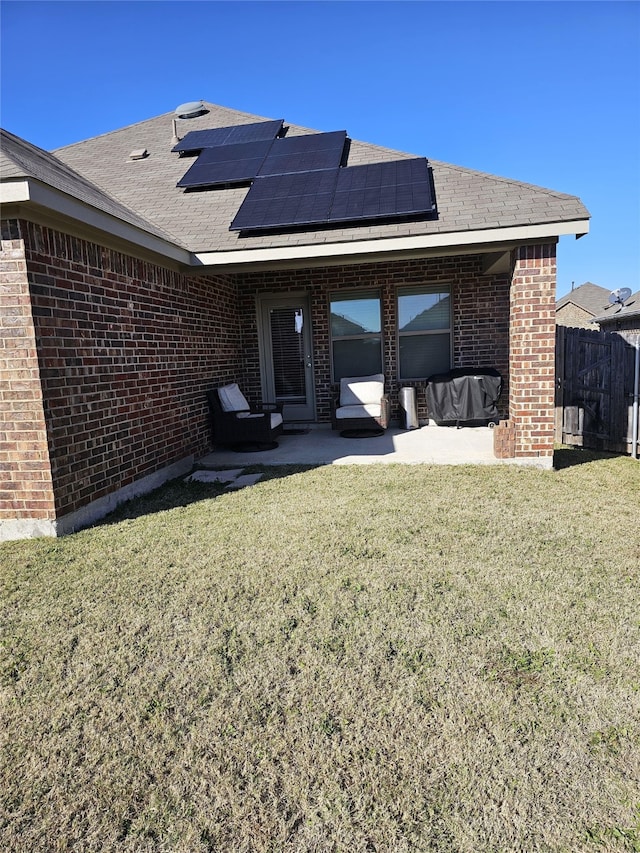 back of house with a patio area, a lawn, and solar panels