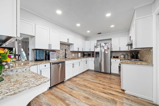 kitchen featuring backsplash, light stone counters, stainless steel appliances, and white cabinetry