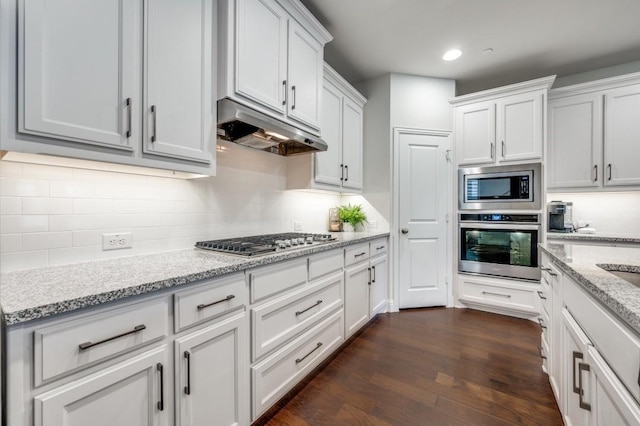 kitchen with dark hardwood / wood-style flooring, light stone counters, stainless steel appliances, and white cabinetry