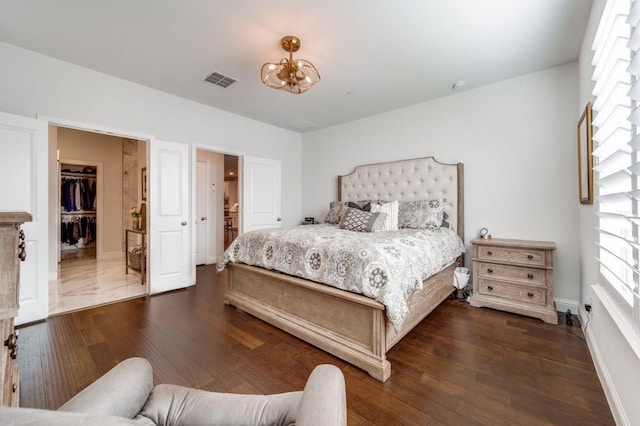 bedroom featuring dark wood-type flooring, a closet, a spacious closet, and a chandelier