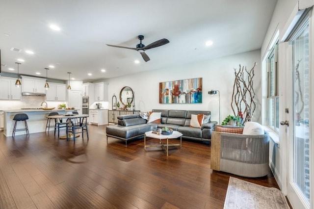 living room with ceiling fan, dark wood-type flooring, and a healthy amount of sunlight