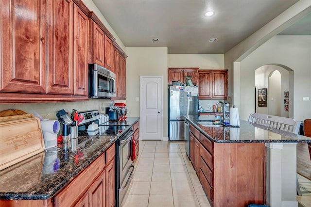 kitchen with tasteful backsplash, sink, appliances with stainless steel finishes, an island with sink, and light tile patterned floors