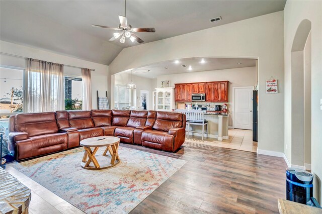 living room featuring light wood-type flooring, vaulted ceiling, and ceiling fan with notable chandelier