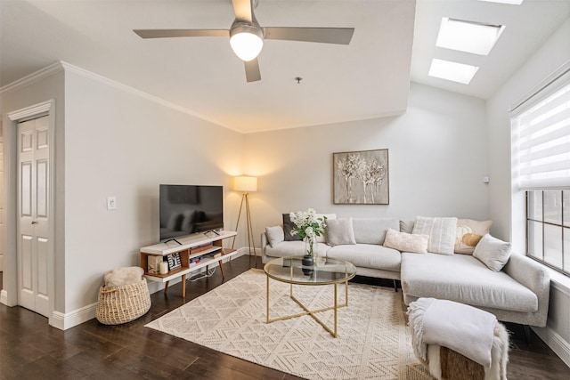 living room with dark wood-type flooring, ceiling fan, crown molding, and a skylight