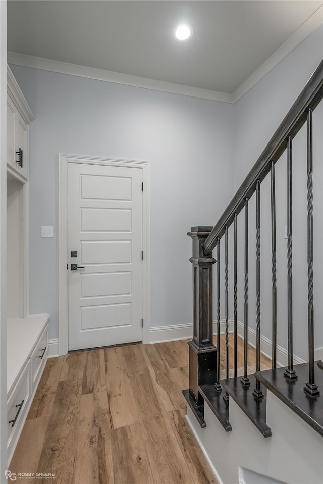 entryway with baseboards, light wood finished floors, stairway, and crown molding