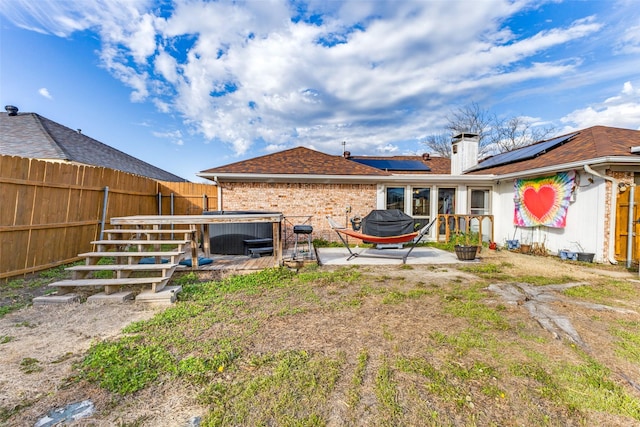 rear view of property featuring a hot tub, solar panels, and a patio