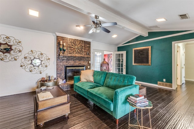 living room featuring dark wood-type flooring, a fireplace, ornamental molding, lofted ceiling with beams, and ceiling fan