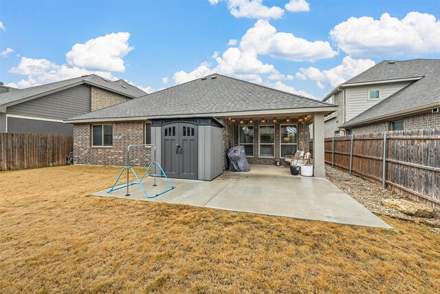 rear view of property featuring a storage unit, a patio, and a lawn