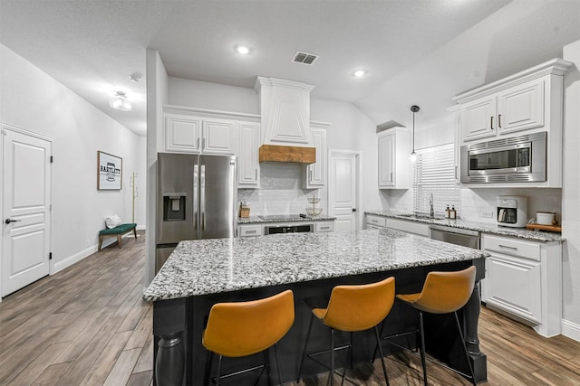 kitchen with wood-type flooring, sink, white cabinets, a center island, and stainless steel appliances