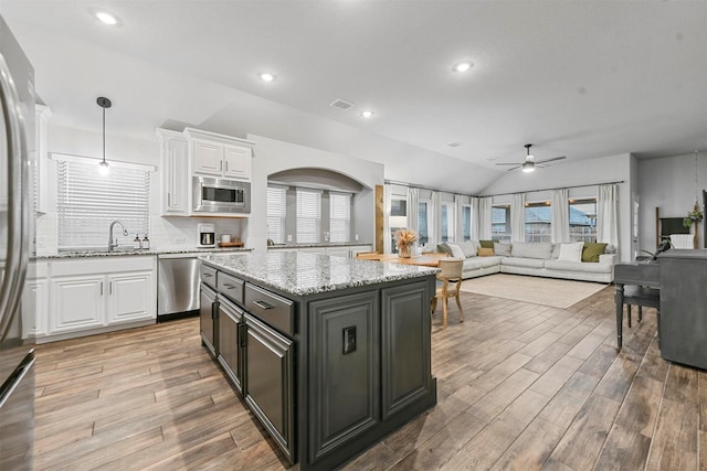 kitchen with white cabinetry, light stone counters, decorative light fixtures, a center island, and stainless steel appliances