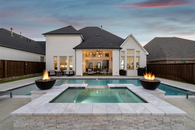 view of pool with a pool with connected hot tub, a patio area, ceiling fan, a fenced backyard, and a fire pit