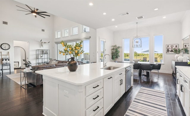 kitchen with an island with sink, dishwasher, pendant lighting, white cabinets, and sink