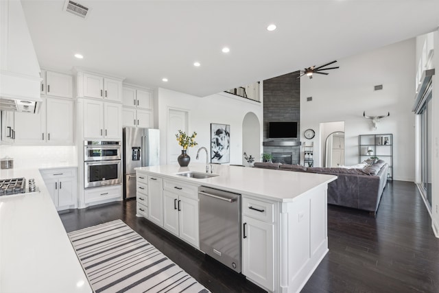 kitchen featuring stainless steel appliances, a sink, visible vents, open floor plan, and light countertops