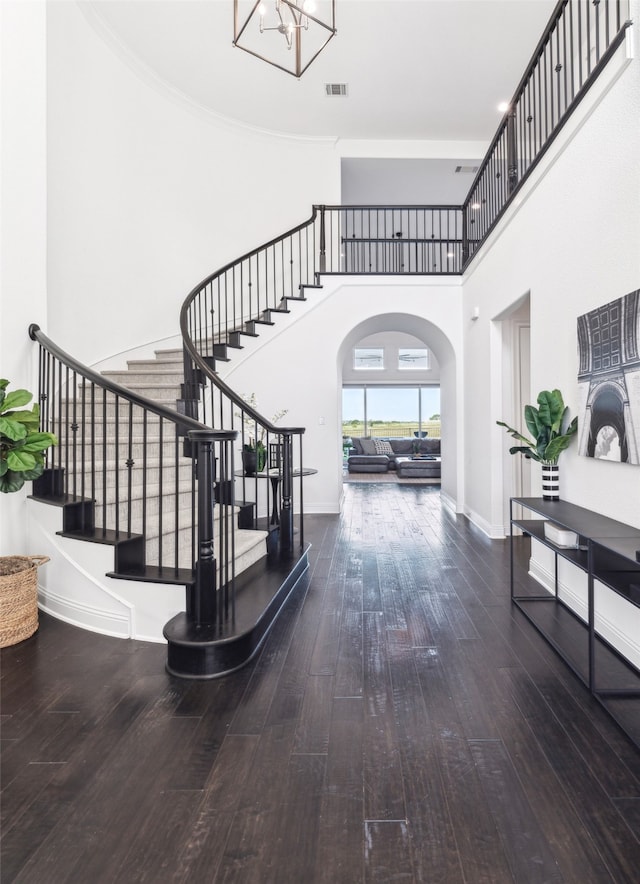 stairs with a high ceiling, hardwood / wood-style floors, crown molding, and a chandelier