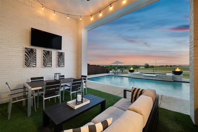 pool at dusk featuring an outdoor hangout area and a patio