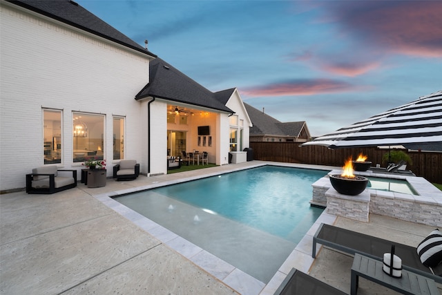 pool at dusk featuring an outdoor fire pit and a patio