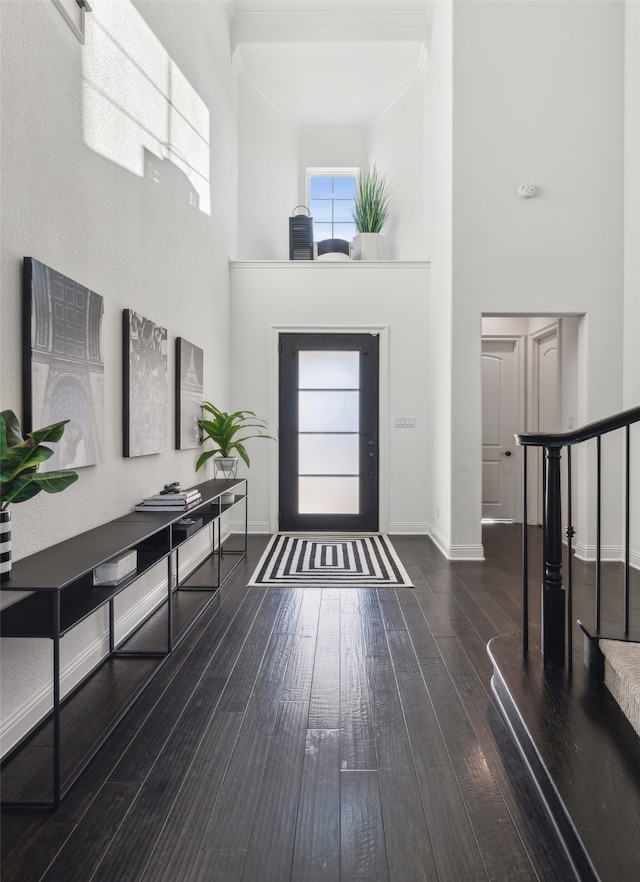 entryway with dark wood-style floors, a high ceiling, ornamental molding, baseboards, and stairs