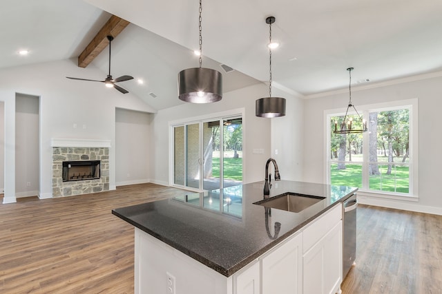 kitchen featuring a kitchen island with sink, a sink, white cabinets, open floor plan, and hanging light fixtures