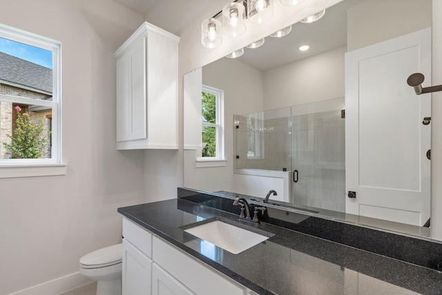 bathroom with a stall shower, a healthy amount of sunlight, vanity, and toilet