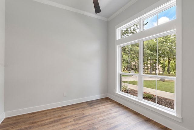 empty room with baseboards, wood finished floors, a ceiling fan, and crown molding