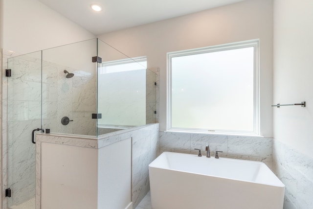 bathroom featuring a shower stall, tile walls, a freestanding bath, and recessed lighting